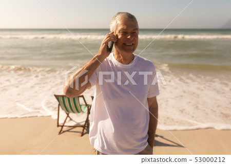Senior man talking on mobile phone at beach Senior man talking on mobile phone at beach 53000212