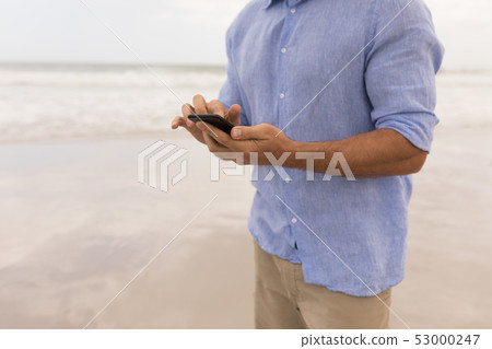 Man using mobile phone on the beach 53000247