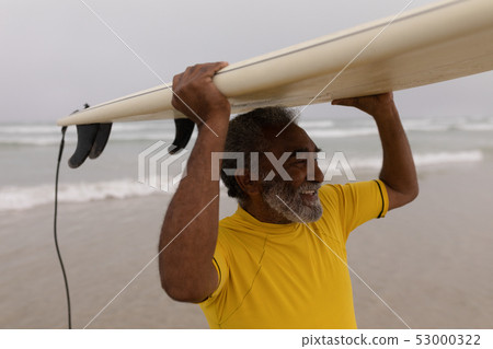 Senior male surfer carrying the surfboard on his head at beach 53000322