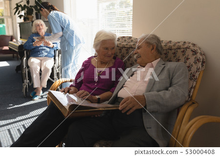Front view of senior couple looking photo album on sofa Front view of senior couple looking photo album on sofa 53000408