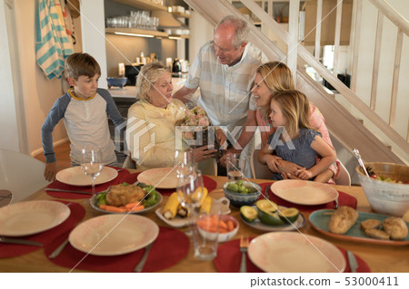 Senior man offering bouquet of flower to senior woman on dining table Senior man offering bouquet of flower to senior woman on dining table 53000411
