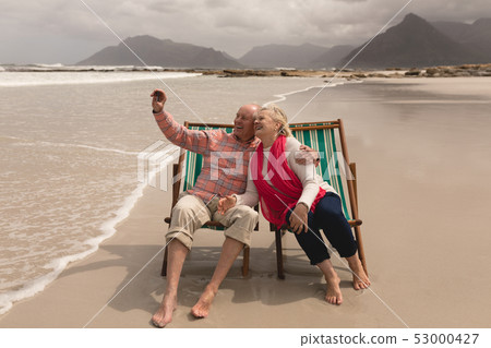 Senior couple taking selfie with mobile phone sitting Senior couple taking selfie with mobile phone sitting 53000427