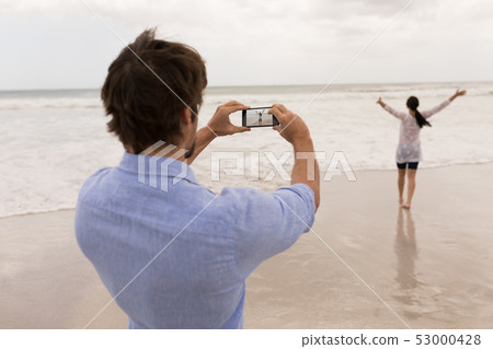 Man clicking photo of woman with mobile phone Man clicking photo of woman with mobile phone 53000428