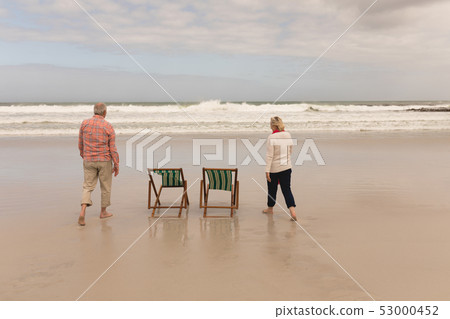 Happy senior couple walking at the beach  53000452