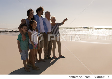 Senior woman with her family pointing at distance on beach Senior woman with her family pointing at distance on beach 53000603