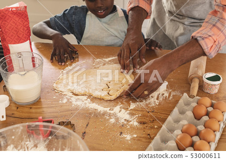 African American father and son baking cookies in kitchen African American father and son baking cookies in kitchen 53000611