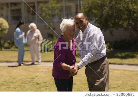 senior couple dancing together in garden  53000683