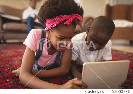 Close-up of African American sibling lying on floor and using digital tablet  53000776