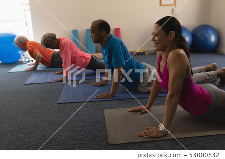 Side view of young female trainer exercising with senior people Side view of young female trainer exercising with senior people 53000832