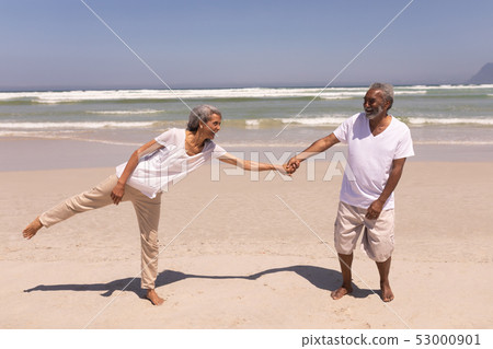 Senior couple holding hands on beach 53000901