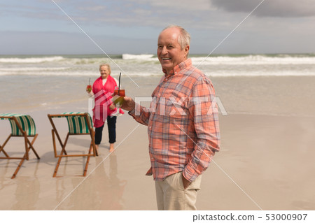 Senior couple having cocktail drinks on the beach 53000907