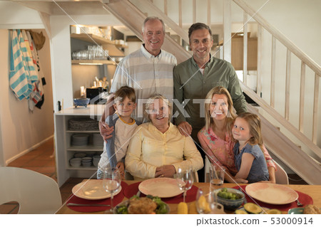 Family posing together before having meal on dining table Family posing together before having meal on dining table 53000914