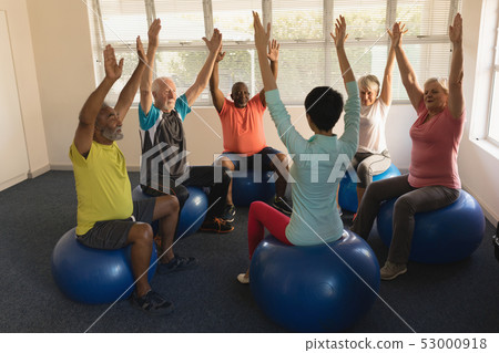Female trainer training senior people in performing exercise Female trainer training senior people in performing exercise 53000918