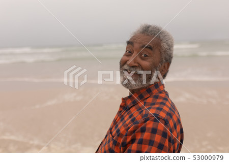 Happy senior man looking at camera on beach 53000979