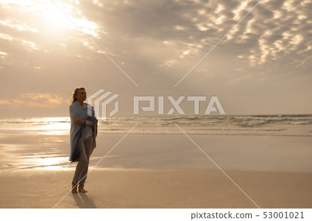 Senior woman wrapped in a shawl standing on the beach Senior woman wrapped in a shawl standing on the beach 53001021