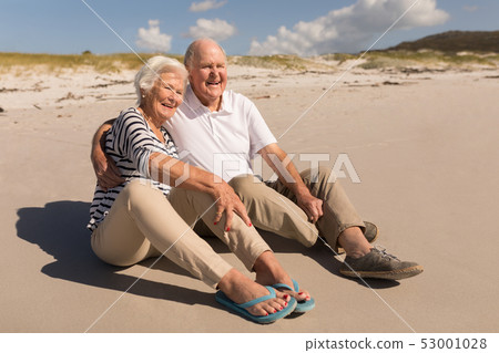 Happy senior couple sitting on beach Happy senior couple sitting on beach 53001028
