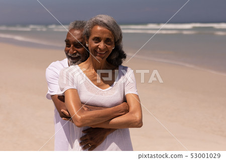 Senior man embracing senior woman on beach 53001029