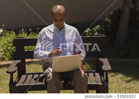 Senior man using laptop in the park Senior man using laptop in the park 53001032