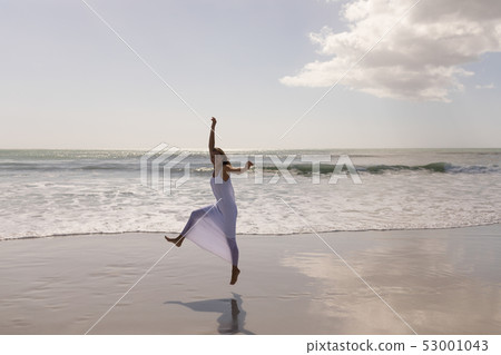 Young woman jumping and having fun on beach Young woman jumping and having fun on beach 53001043