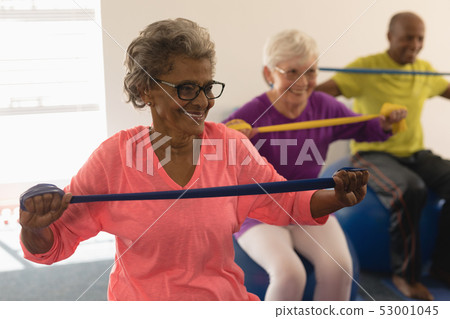 Senior woman exercising with resistance band in fitness studio Senior woman exercising with resistance band in fitness studio 53001045