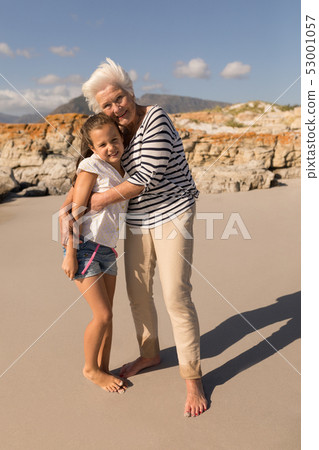 Happy senior woman embracing her granddaughter on beach Happy senior woman embracing her granddaughter on beach 53001057