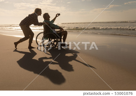Senior couple taking selfie with mobile phone on the beach 53001076