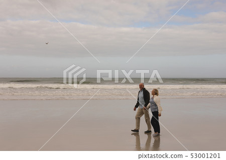 Senior couple walking hand in hand at the beach 53001201