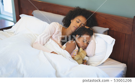 African American mother and daughter sleeping together on bed in bedroom African American mother and daughter sleeping together on bed in bedroom 53001206