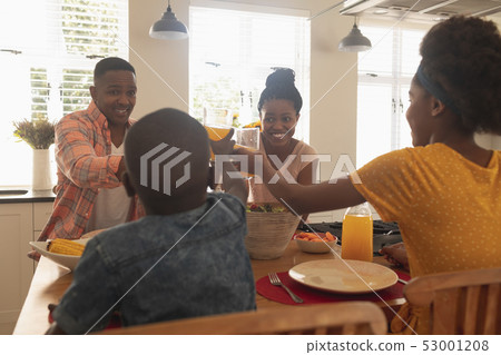 Happy African American family toasting glasses at dining table Happy African American family toasting glasses at dining table 53001208