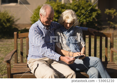 Senior couple using mobile phone in the park Senior couple using mobile phone in the park 53001210