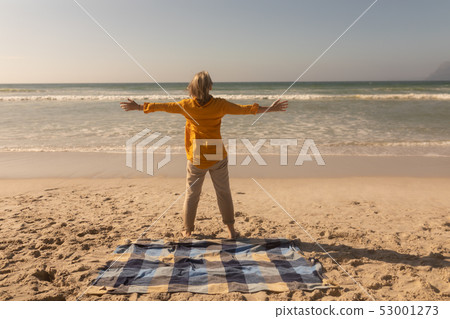 Senior woman standing with arms outstretched on the beach Senior woman standing with arms outstretched on the beach 53001273