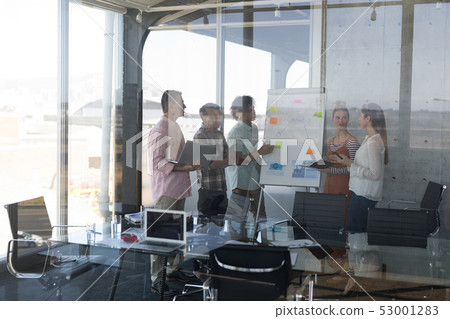 Business colleagues discussing over flip chart in office 53001283