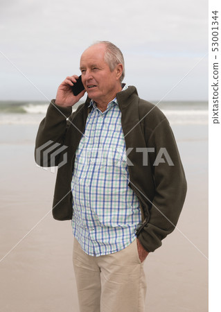 Happy senior man talking on mobile phone at beach Happy senior man talking on mobile phone at beach 53001344