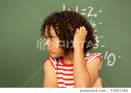 Schoolgirl standing against green board in a classroom at school Schoolgirl standing against green board in a classroom at school 53001346