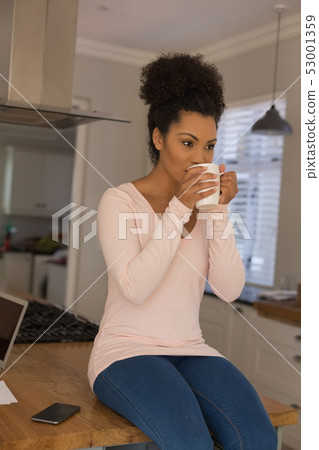 Beautiful woman having coffee in kitchen at home Beautiful woman having coffee in kitchen at home 53001359