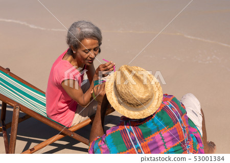 Senior couple relaxing on sun lounger and drinking cocktail on beach Senior couple relaxing on sun lounger and drinking cocktail on beach 53001384