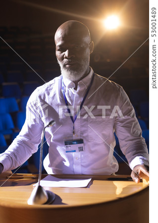 Businessman standing at podium on stage in auditorium 53001489