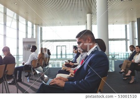 Businessman using laptop during business seminar 53001510