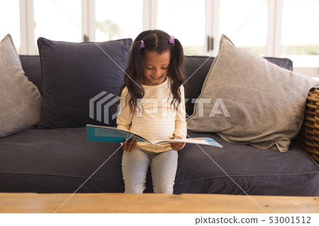 Girl reading a story book in living room 53001512