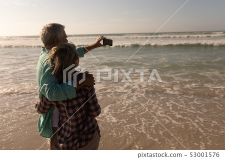 Senior couple taking selfie with mobile phone on the beach 53001576