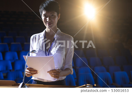 Businesswoman standing at podium on stage in auditorium 53001653