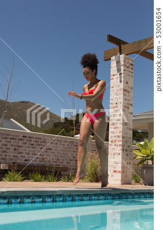 Woman in bikini walking near swimming pool 53001654