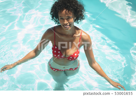 Happy young African American man looking at camera in swimming pool Happy young African American man looking at camera in swimming pool 53001655