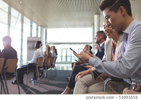 Business executives discussing over mobile phone during seminar 53001658