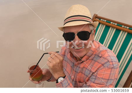 Senior man having cocktail drink while relaxing in a sun lounger Senior man having cocktail drink while relaxing in a sun lounger 53001659