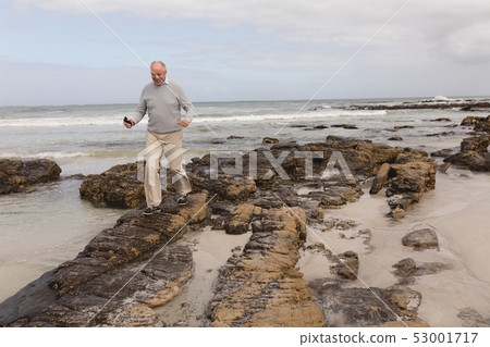 Senior man walking on the rock at beach 53001717