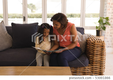 Grandmother and granddaughter reading a story book in living room Grandmother and granddaughter reading a story book in living room 53001866
