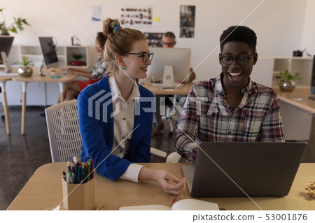 Business colleagues discussing over laptop in office Business colleagues discussing over laptop in office 53001876