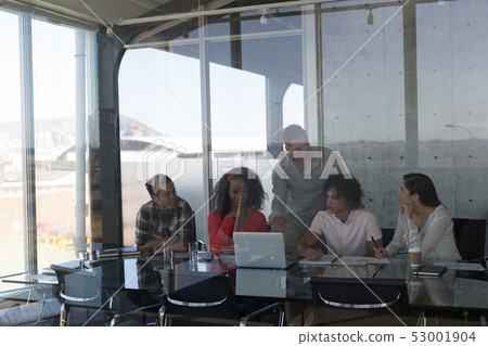 Business colleagues discussing over laptop in office 53001904