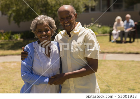 Front view of senior couple holding hands and looking at camera in garden Front view of senior couple holding hands and looking at camera in garden 53001918